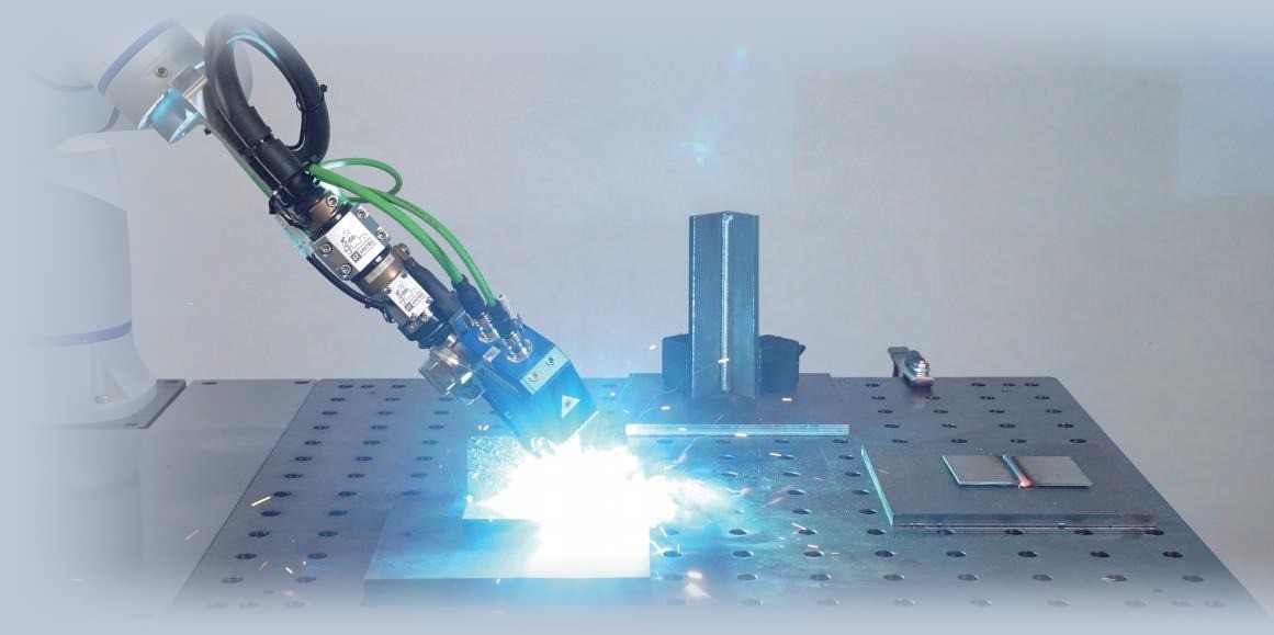 Cobot mit Schweißbrenner und Sensor schweißt ein Werkstück am Lochtisch