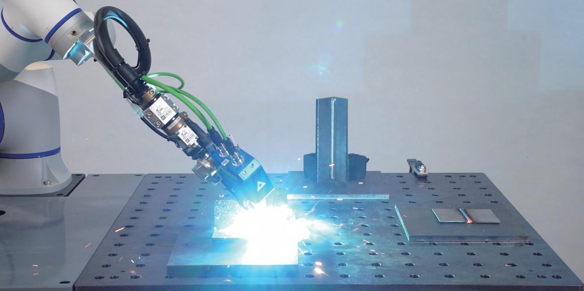 schweissloesung-slider-cobot-lochtisch Cobot mit Schweißbrenner und Sensor schweißt ein Werkstück am Lochtisch
