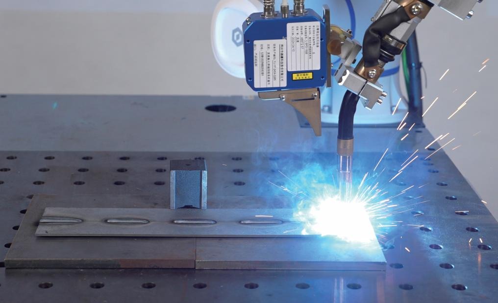 schweissloesung-slider-lichtbogen-funkenflug Cobot schweißt mit Lichtbogen und Funkenflug an einem Lochtisch, Laser-Sensor am Brenner